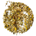 Dried chamomile tea loose leaves and yellow flower heads arranged in a circular pile on a white background.