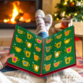 A person sitting by a fireplace with their legs crossed, holding open a Christmas advent calendar made of book pages. The pages are green with numbered yellow teacups and small festive illustrations, while the person wears cozy knit socks and a sweater.