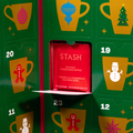 A festive green advent calendar with numbered doors and holiday cup illustrations, with one door open to reveal a red Stash Santa's cinnamon apple tea packet.