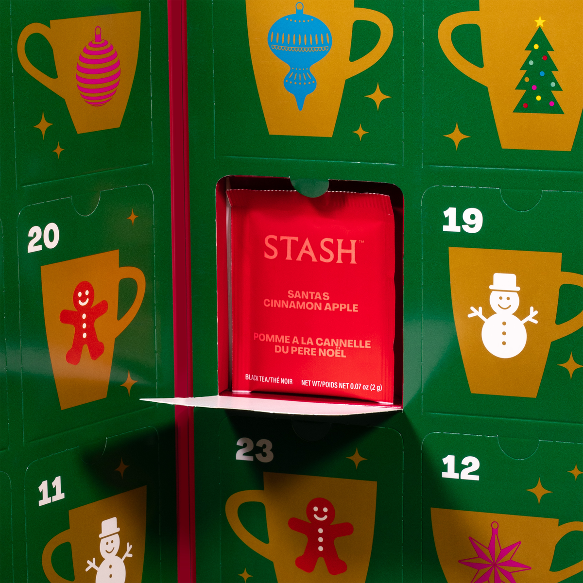 A festive green advent calendar with numbered doors and holiday cup illustrations, with one door open to reveal a red Stash Santa's cinnamon apple tea packet.