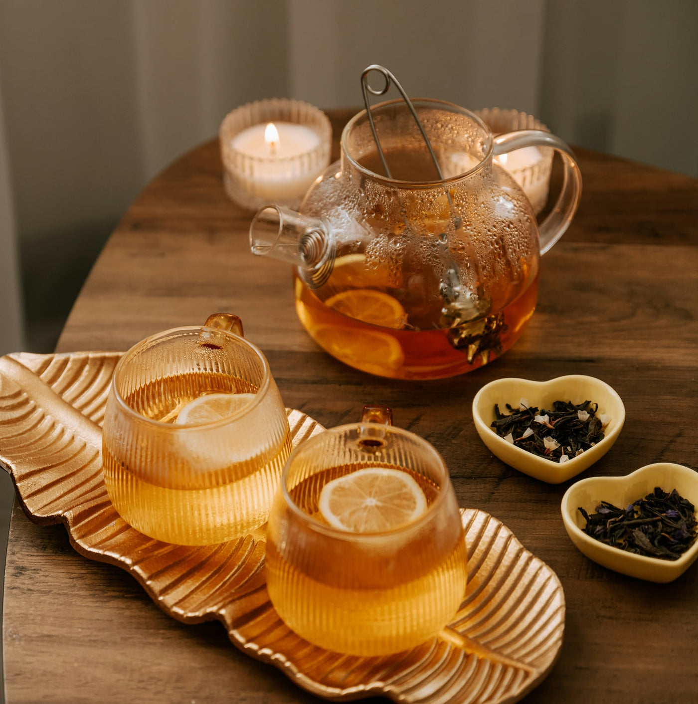 Tea-making setup with a teapot, glasses, and tea leaves on a wooden table.